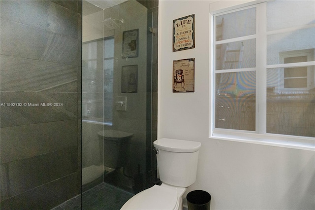 bathroom featuring a shower with shower door and toilet