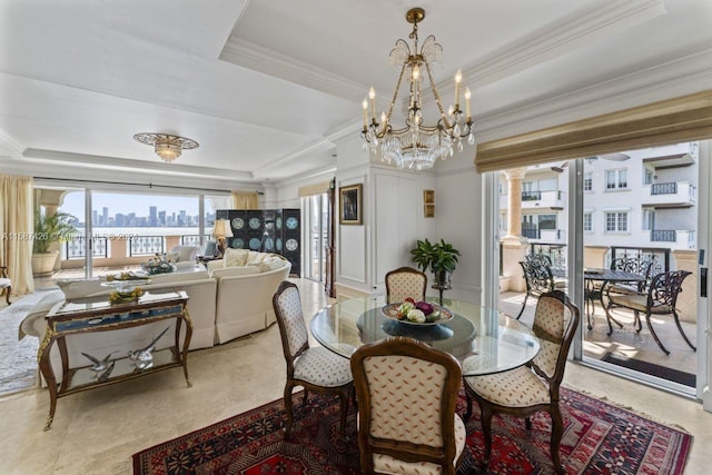 dining area featuring a raised ceiling, an inviting chandelier, crown molding, and ornate columns