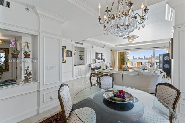 dining space featuring ornamental molding, a tray ceiling, light tile floors, and a chandelier