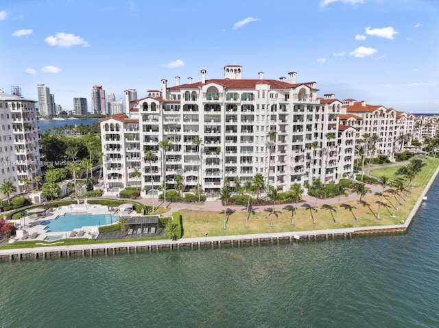 view of building exterior with a community pool and a water view