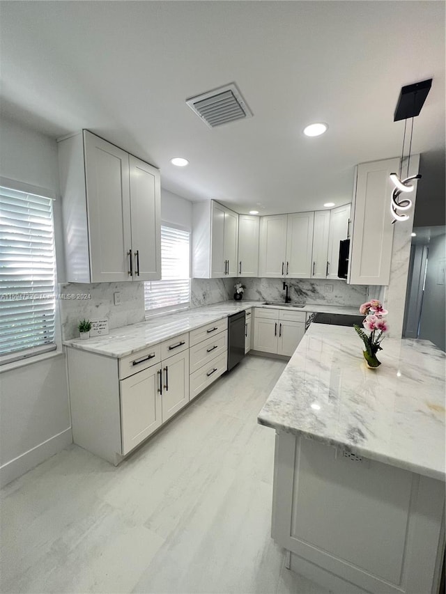 kitchen featuring tasteful backsplash, light stone counters, pendant lighting, dishwasher, and white cabinets