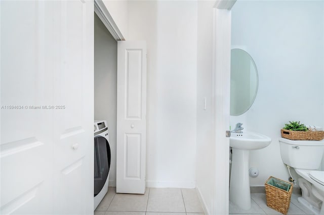 bathroom with tile patterned flooring, sink, toilet, and washer / dryer