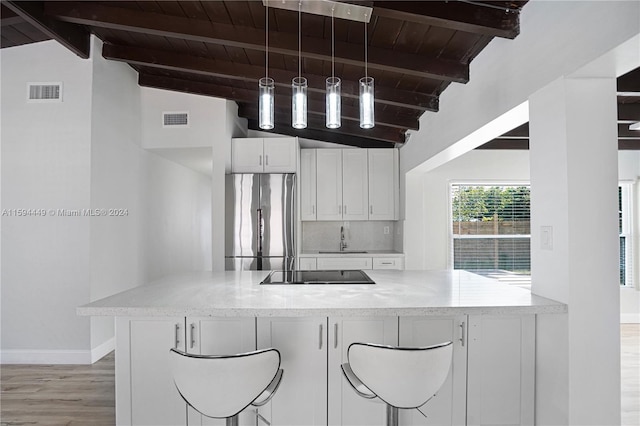 kitchen with pendant lighting, stainless steel refrigerator, sink, white cabinets, and black electric stovetop