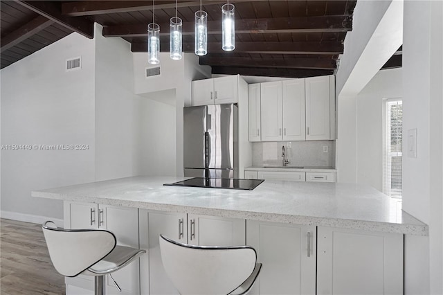 kitchen with white cabinetry, stainless steel refrigerator, beamed ceiling, wooden ceiling, and decorative light fixtures