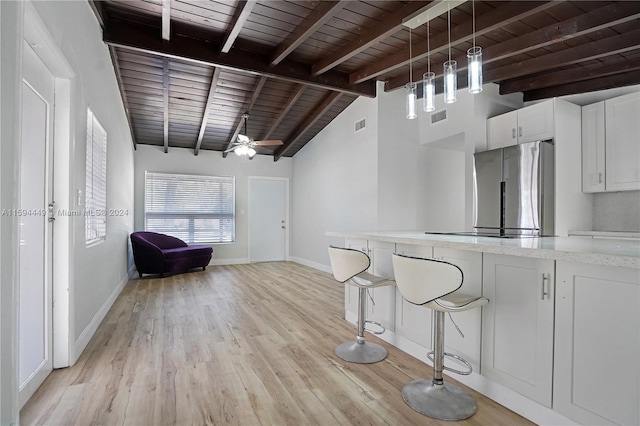 kitchen featuring stainless steel refrigerator, white cabinetry, a kitchen breakfast bar, hanging light fixtures, and wooden ceiling