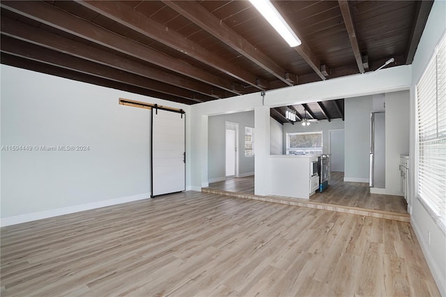 unfurnished living room with light hardwood / wood-style flooring, wooden ceiling, a barn door, and beamed ceiling