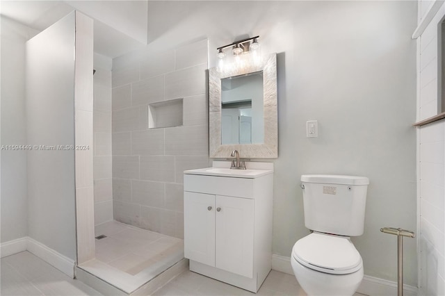 bathroom with tile patterned flooring, toilet, vanity, and a tile shower