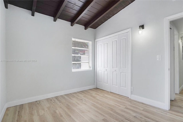 unfurnished bedroom with lofted ceiling with beams, wooden ceiling, light wood-type flooring, and a closet