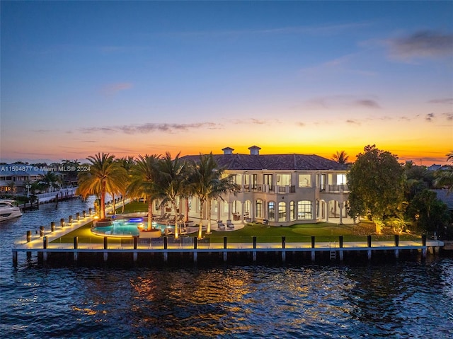 back house at dusk featuring a yard and a water view