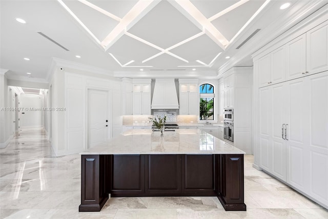 kitchen with premium range hood, white cabinetry, and a spacious island