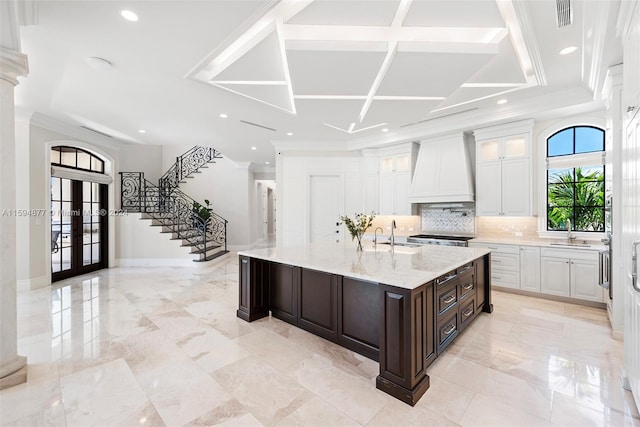 kitchen with a large island, custom exhaust hood, and white cabinetry