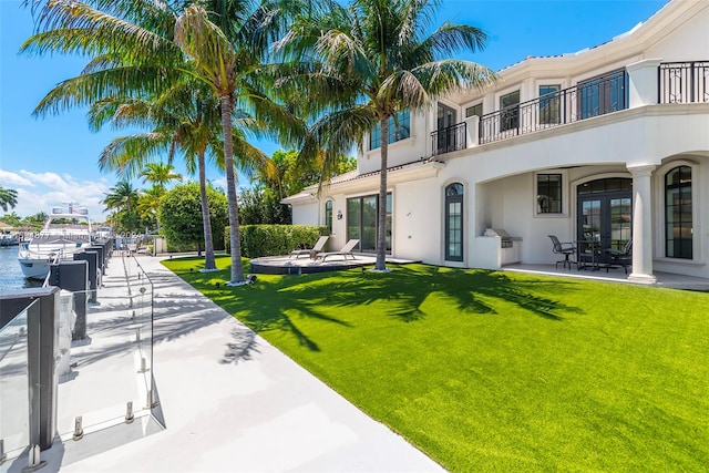 view of yard featuring a patio area, a balcony, and a water view