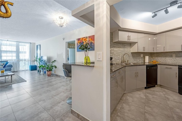 kitchen with sink, dark stone countertops, dishwasher, kitchen peninsula, and decorative backsplash