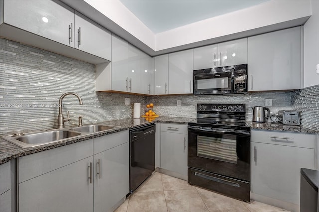 kitchen featuring sink, light tile patterned floors, dark stone countertops, tasteful backsplash, and black appliances