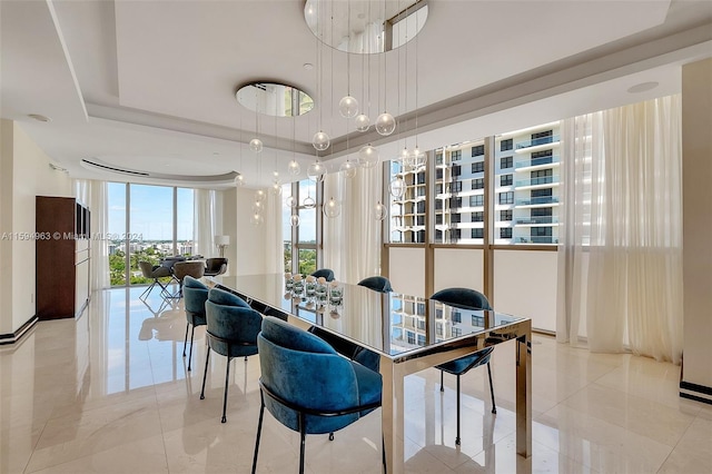 tiled dining room featuring a tray ceiling, a high ceiling, and an inviting chandelier