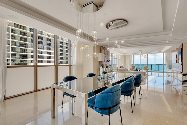 tiled dining area with a tray ceiling and a water view