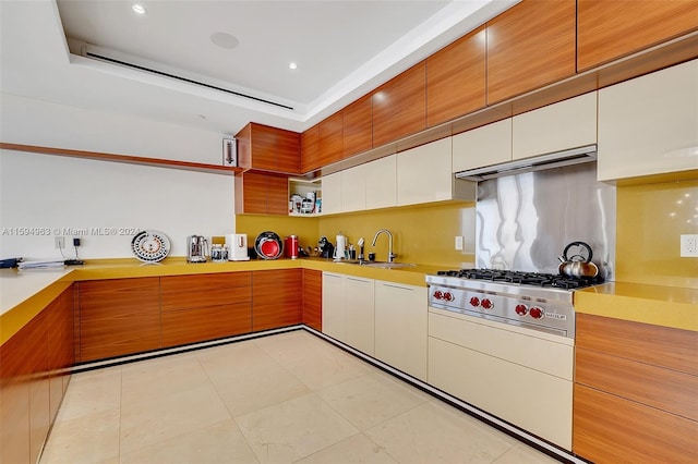 kitchen featuring sink, a tray ceiling, light tile floors, and tasteful backsplash