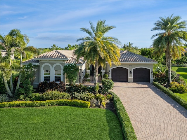 mediterranean / spanish house featuring a front yard and a garage