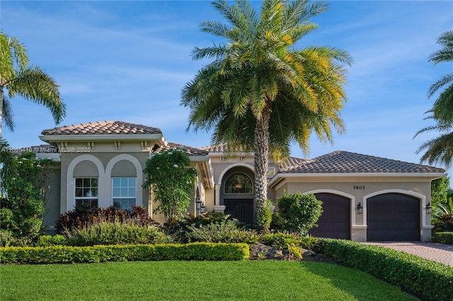 mediterranean / spanish home featuring a garage and a front lawn