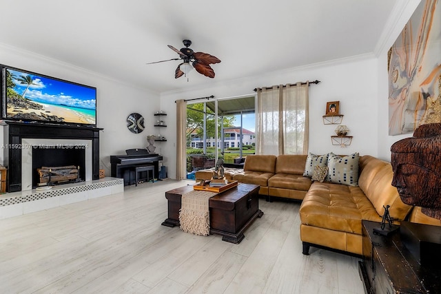 living room with light hardwood / wood-style flooring, ceiling fan, ornamental molding, and a tiled fireplace