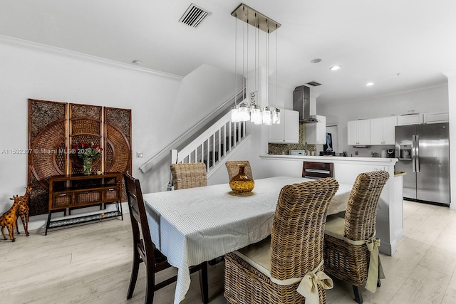 dining space with crown molding and light hardwood / wood-style floors