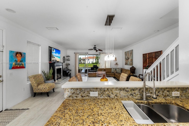 living room featuring light wood-type flooring, ceiling fan, crown molding, and sink