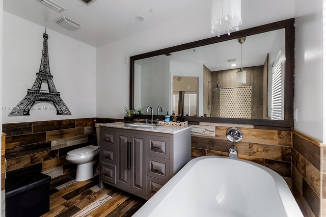 full bathroom with hardwood / wood-style floors, vanity, toilet, tile walls, and independent shower and bath