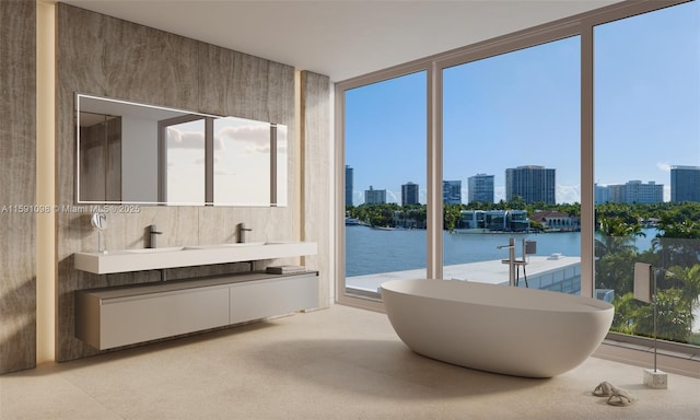 bathroom with a bathing tub, a water view, vanity, and a wall of windows