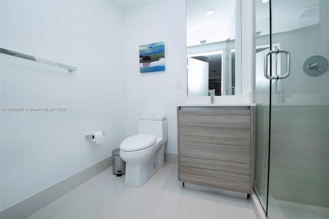 bathroom featuring vanity, toilet, tile floors, and a shower with door