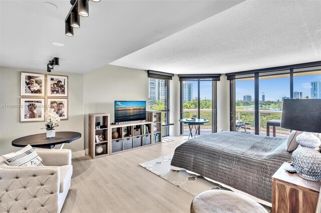 bedroom featuring a textured ceiling, floor to ceiling windows, and wood-type flooring