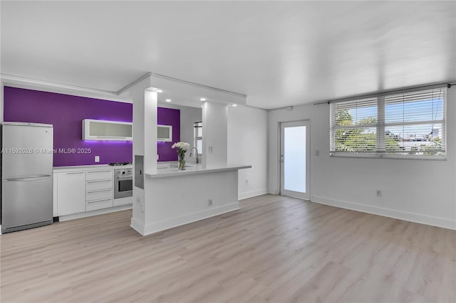 kitchen featuring sink, stainless steel appliances, light hardwood / wood-style floors, white cabinets, and kitchen peninsula