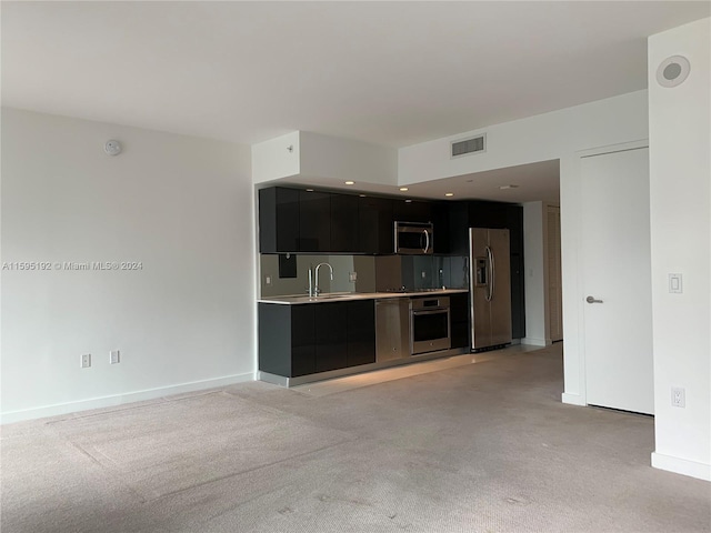 interior space featuring sink, light carpet, and appliances with stainless steel finishes