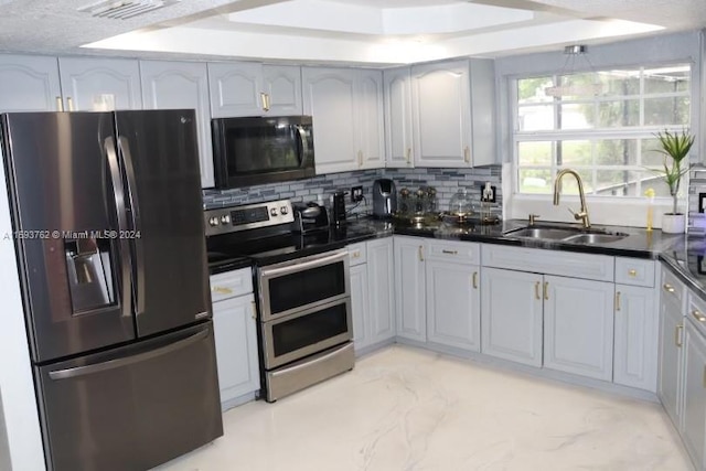 kitchen featuring gray cabinetry, light tile patterned floors, appliances with stainless steel finishes, sink, and decorative backsplash