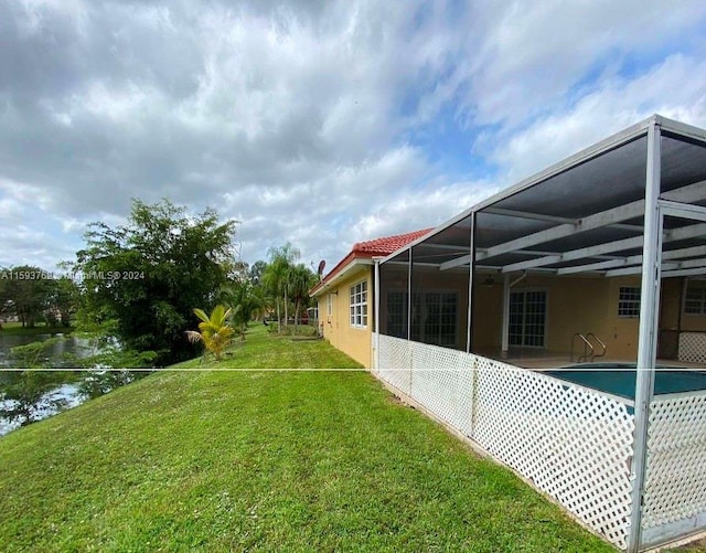 view of yard featuring a water view and glass enclosure