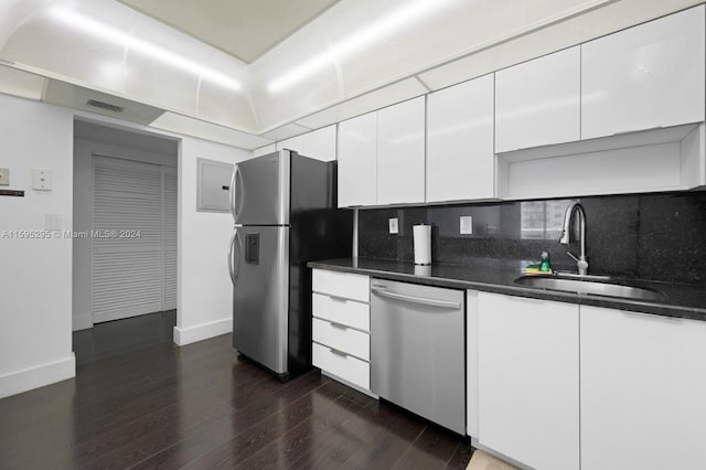 kitchen with appliances with stainless steel finishes, white cabinets, backsplash, dark hardwood / wood-style floors, and sink