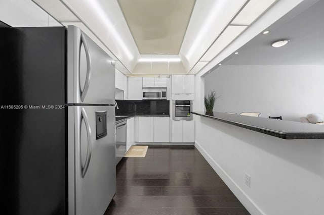 kitchen with appliances with stainless steel finishes, tasteful backsplash, dark hardwood / wood-style flooring, and white cabinets