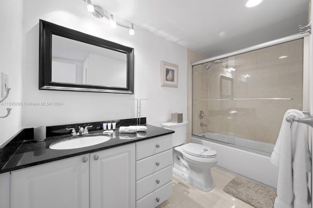 full bathroom with tile patterned flooring, bath / shower combo with glass door, vanity, and toilet