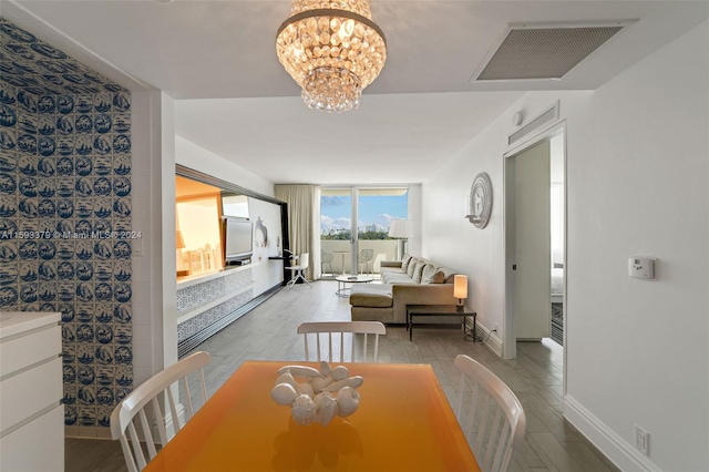 dining room featuring wood-type flooring, expansive windows, and an inviting chandelier