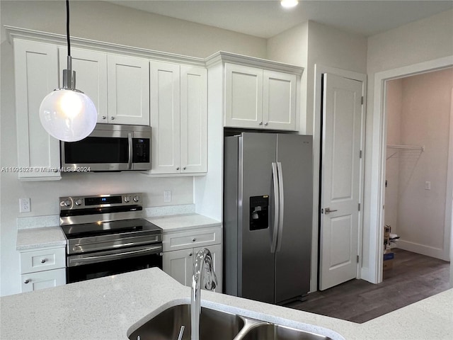 kitchen with stainless steel appliances, sink, pendant lighting, dark hardwood / wood-style floors, and white cabinetry