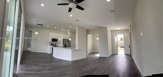 kitchen featuring dark wood-type flooring, ceiling fan, appliances with stainless steel finishes, decorative light fixtures, and white cabinetry