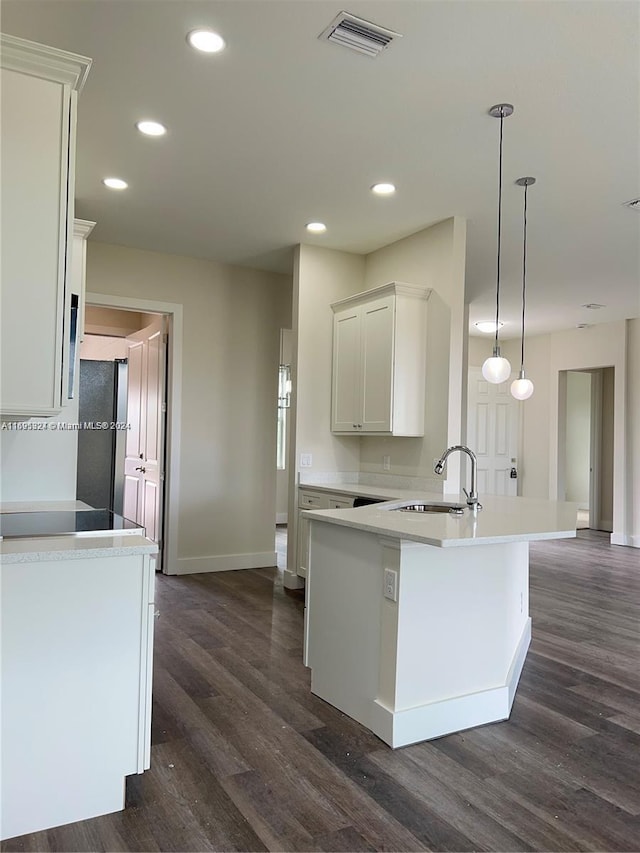 kitchen with stainless steel fridge, dark hardwood / wood-style flooring, sink, white cabinets, and hanging light fixtures