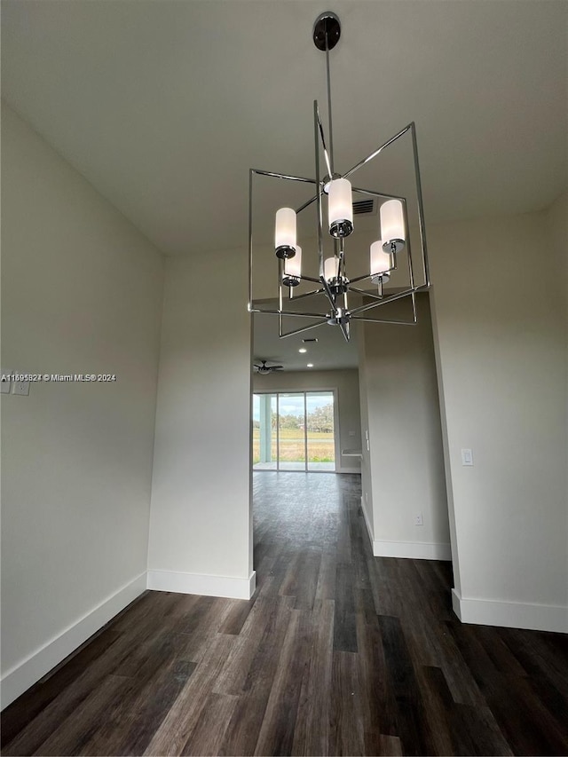 unfurnished dining area with dark wood-type flooring and a notable chandelier