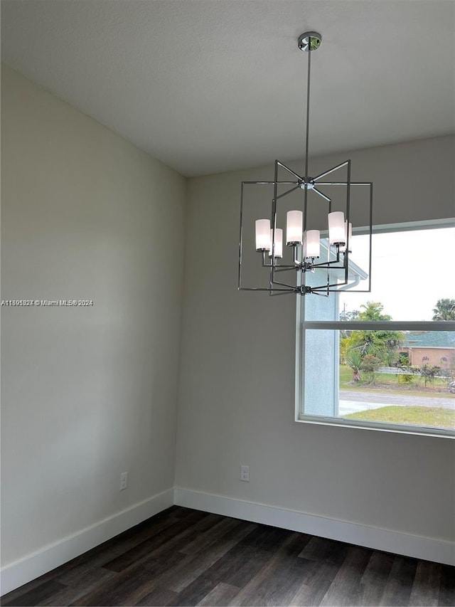 unfurnished dining area featuring a notable chandelier and dark wood-type flooring