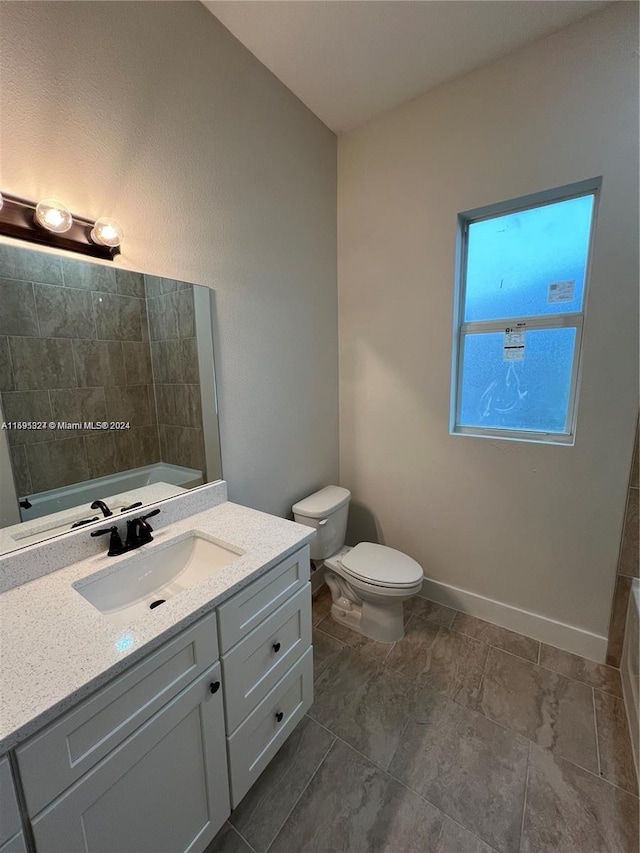 bathroom featuring vanity, toilet, and a washtub