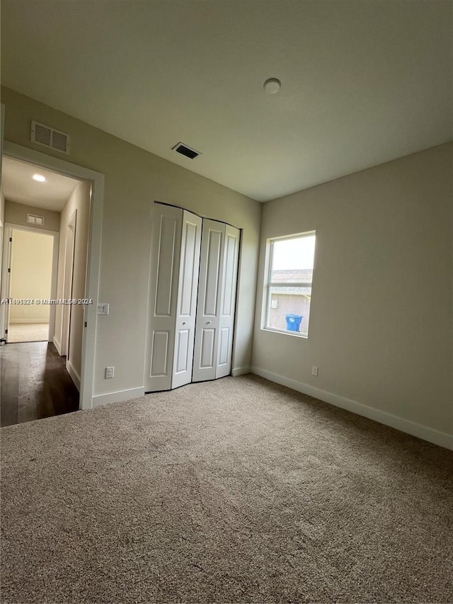 unfurnished bedroom with a closet and dark colored carpet