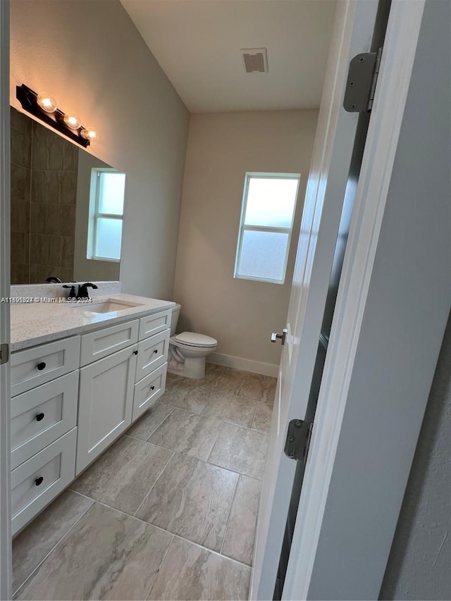 bathroom featuring a wealth of natural light, vanity, and toilet