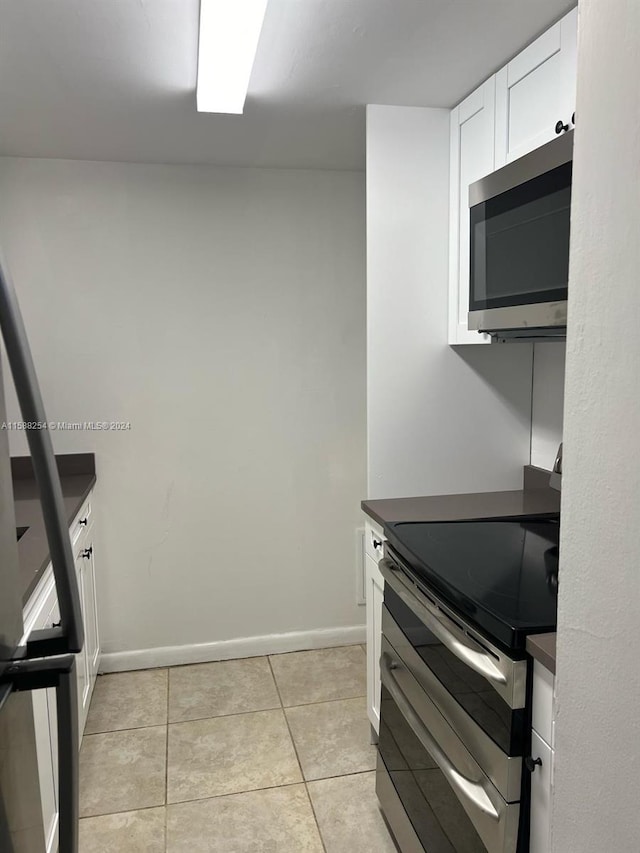 kitchen with white cabinetry, stainless steel appliances, and light tile patterned floors