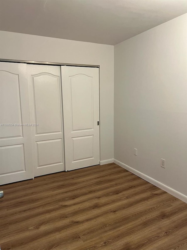 unfurnished bedroom featuring dark hardwood / wood-style floors and a closet