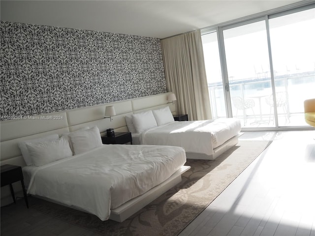 bedroom with access to exterior, dark hardwood / wood-style flooring, and expansive windows