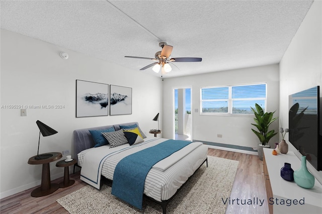 bedroom featuring baseboards, light wood-style floors, ceiling fan, and a textured ceiling